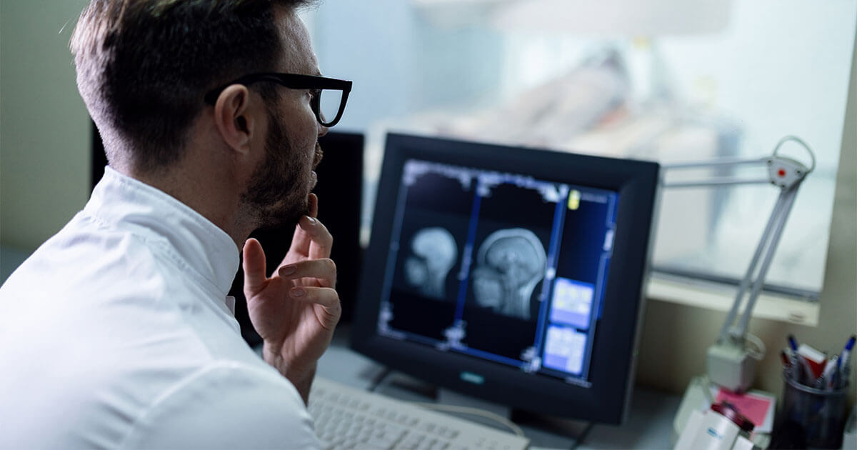 Radiologist sitting in front of a computer examining an MRI